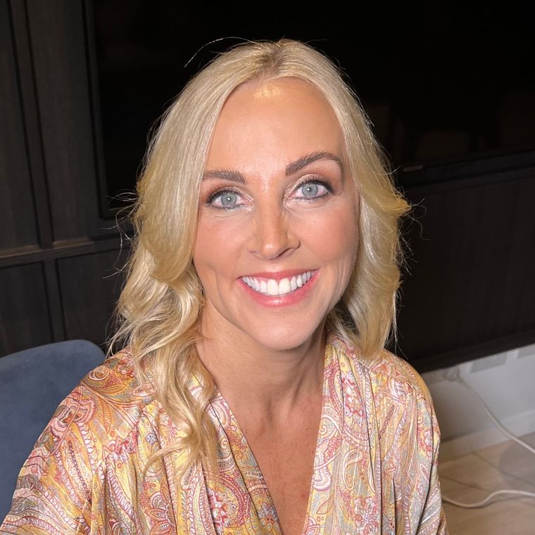 A bridesmaid in a floral robe, glowing makeup and blonde curls